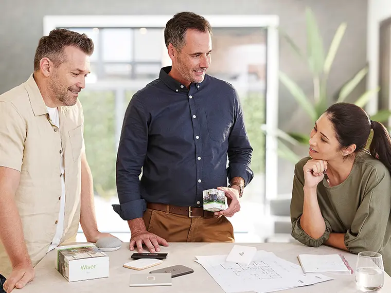 A group of professionals around a table discussing home design plans and Clipsal products.