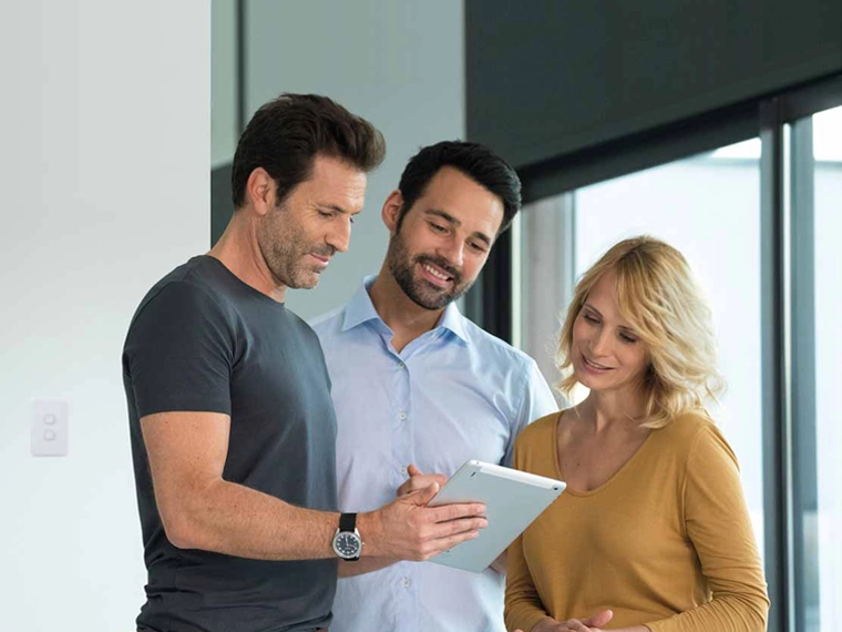 Three people reading an article on a tablet.