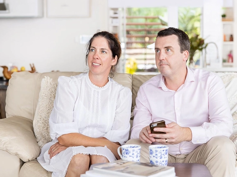 Two people seated on a sofa at home.