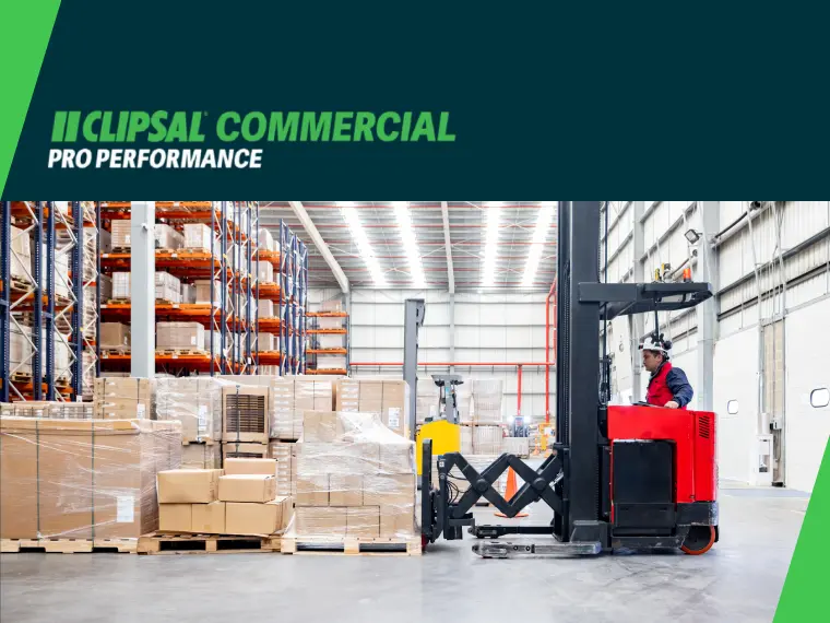 Warehouse with tall racks, stacked boxes, and forklift operator moving pallets.