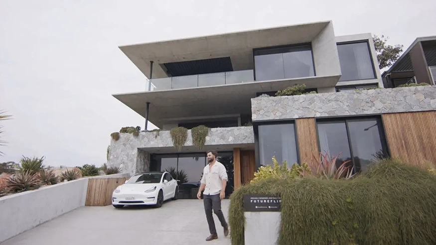 Neil Hipwell standing in the driveway of the Bunker House: a modern multi-storey home with a stone and wood exterior.