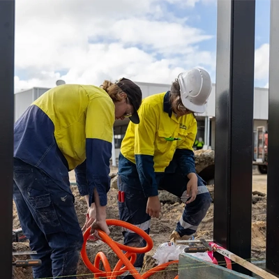 Two electricians in hi-vis gear working onsite.