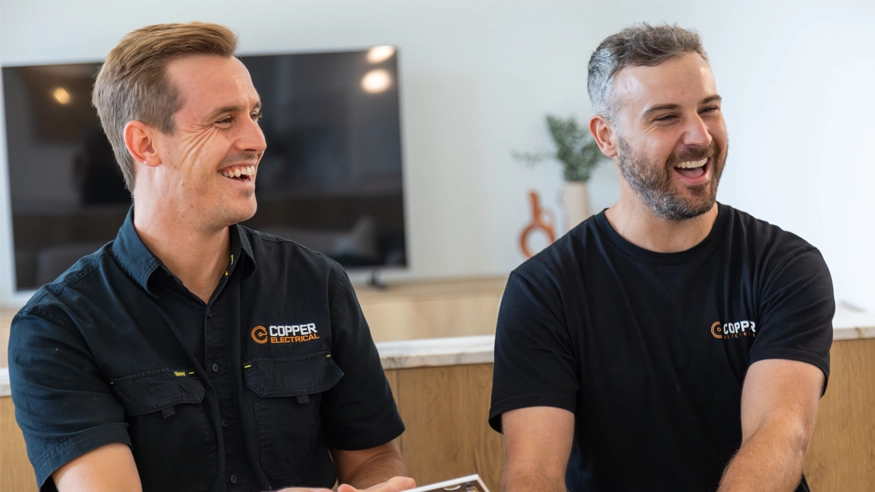 Two men in black shirts laughing together and engaging in a cheerful discussion.