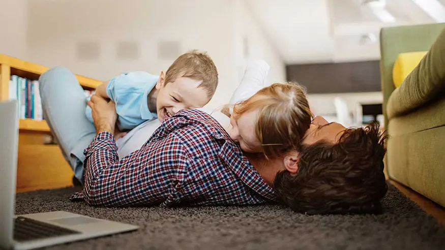 Adult lying on the floor playing with two young children.