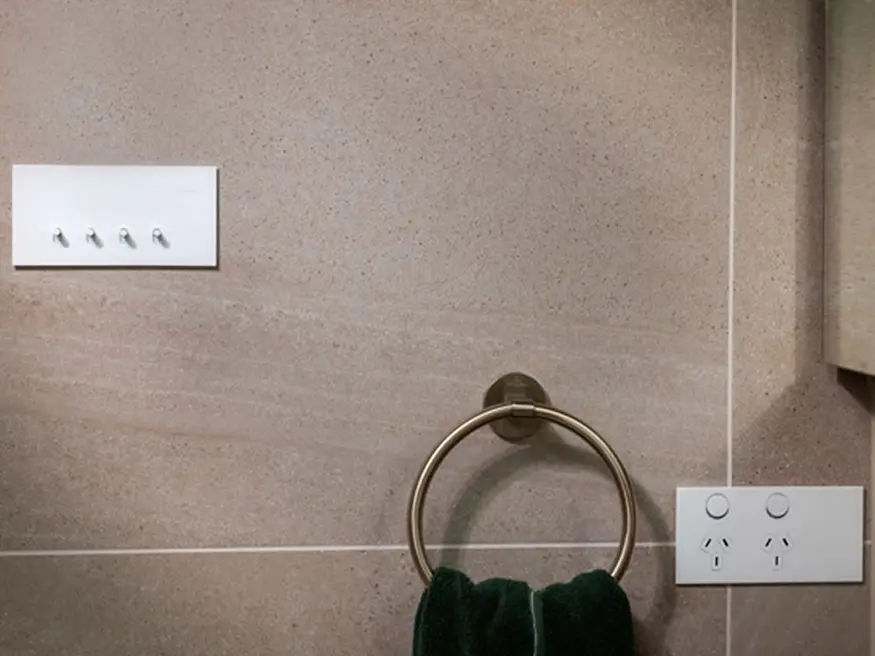 Clipsal Solis switches and power points in a White Ceramic finish mounted on a beige tiled wall.