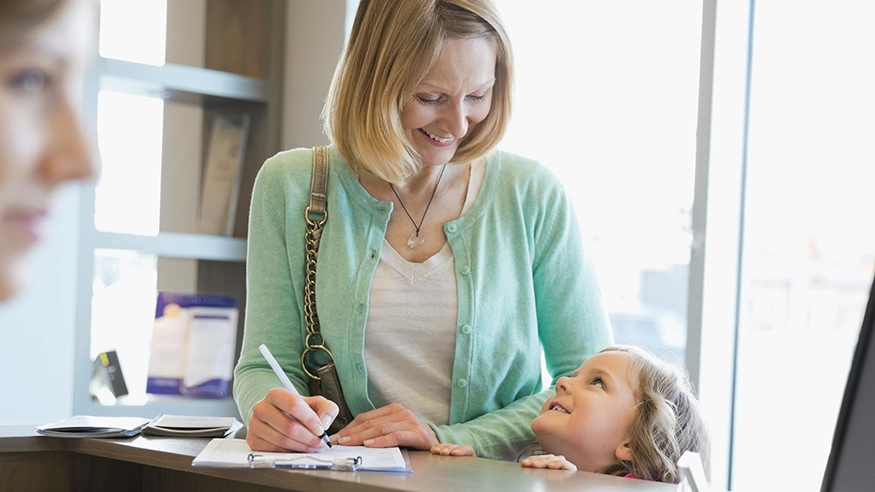 A woman and her daughter filling out a form in an office.