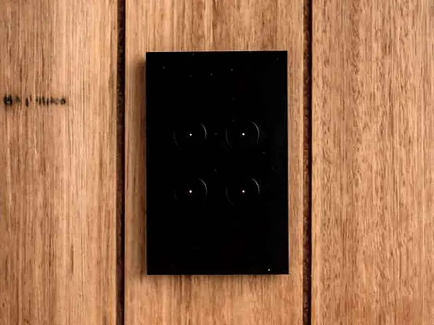 Saturn Zen push button switch in Zen Black mounted on a wooden wall.
