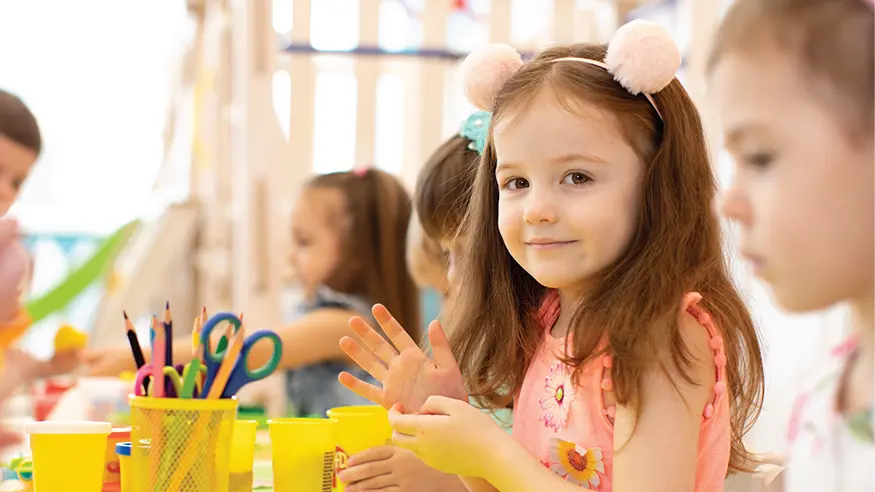 Children sitting at a table doing arts and crafts.