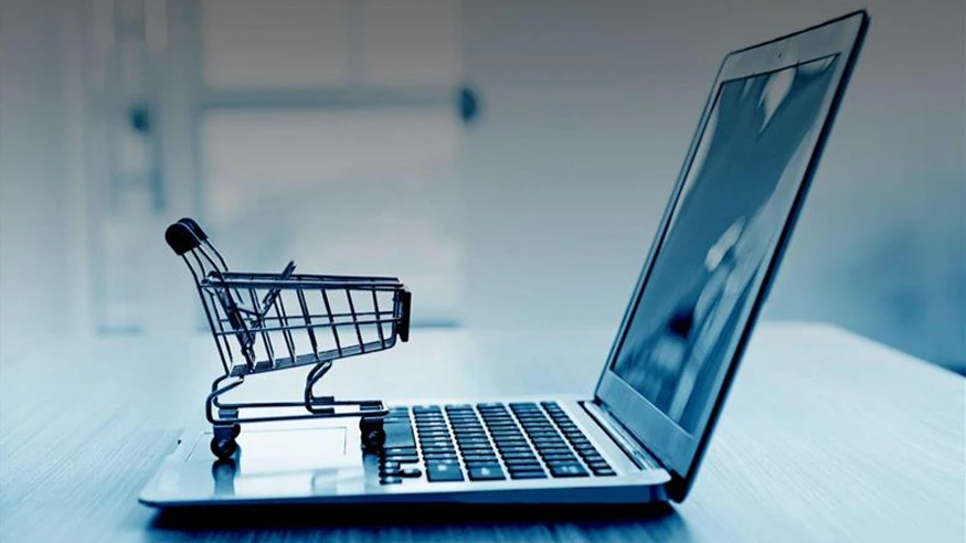 A miniature shopping cart placed on the keyboard of an open laptop