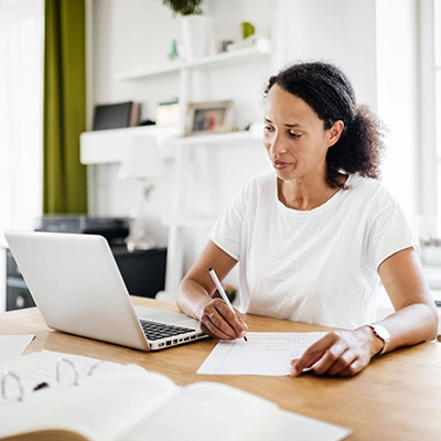 'Woman sitting at a desk writing on paper.
