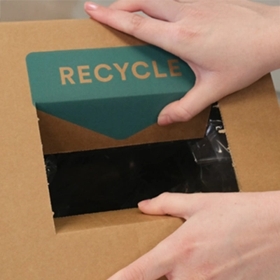 A TerraCycle Zero Waste Box with its cut-out being pushed down to open it for use.