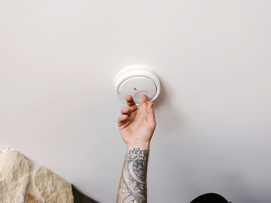 A round Clipsal Wiser Smart Smoke Alarm being installed.