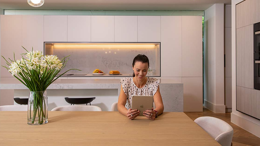 A woman reading a blog article about Clipsal Electric Home Design on her tablet.