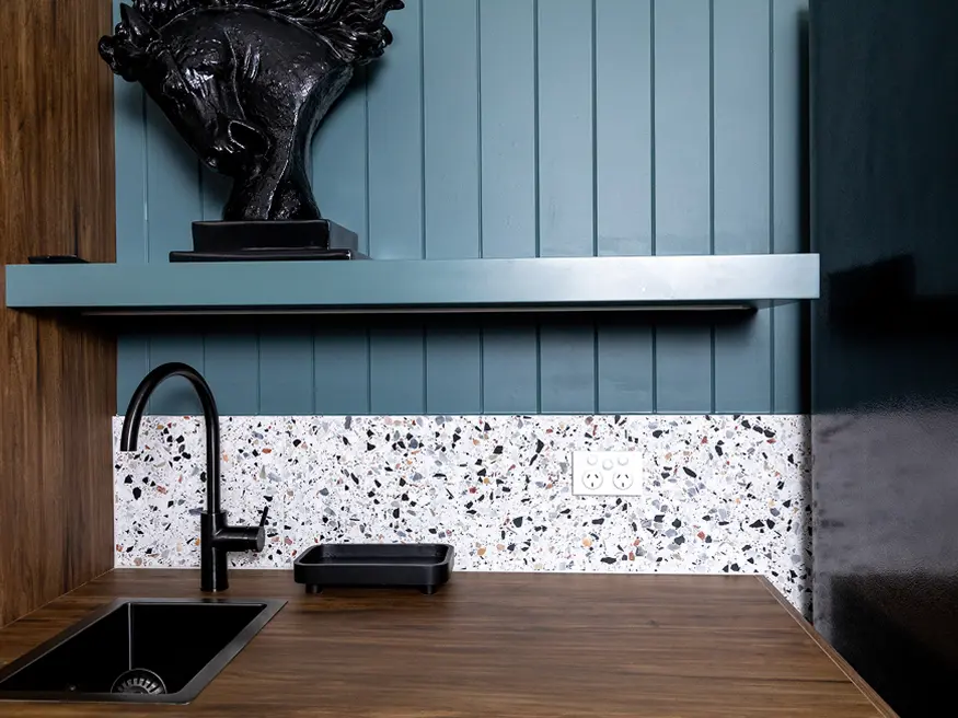 Saturn Zen double power point on terrazzo backsplash in a modern kitchen with wood counter and black sink.