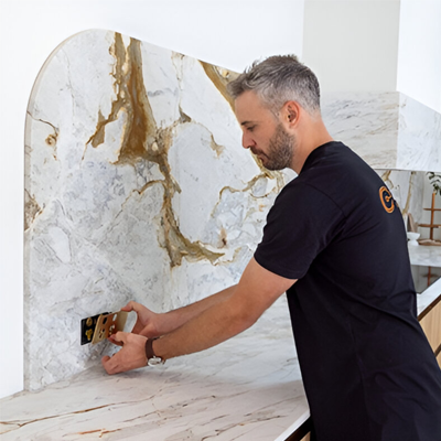 A man is focused on installing a new electrical socket on a marble countertop in a modern kitchen setting.