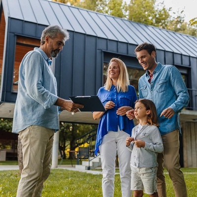 A family standing in front of a home while talking to a property agent.