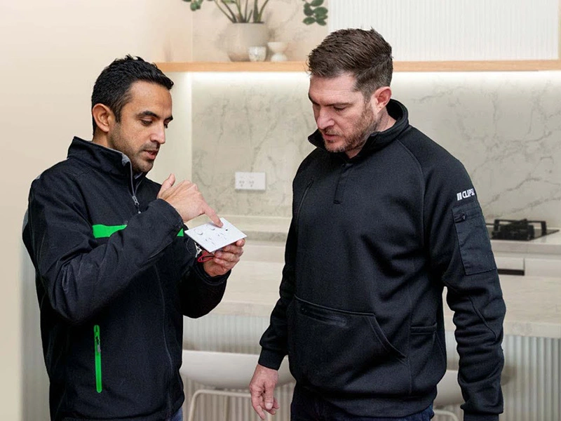 Two men discuss a the Clipsal Solis™ in a modern kitchen