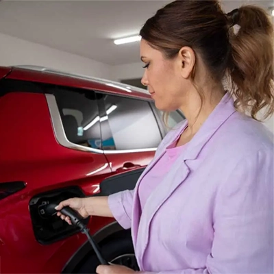 A woman uses an EV charger on her electric vehicle.
