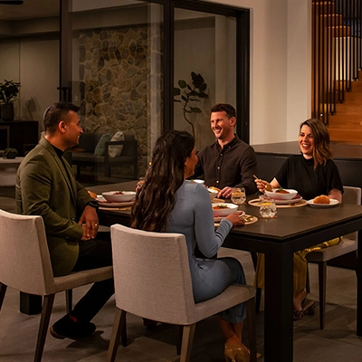 Four people sit together around a table in a furnished kitchen.