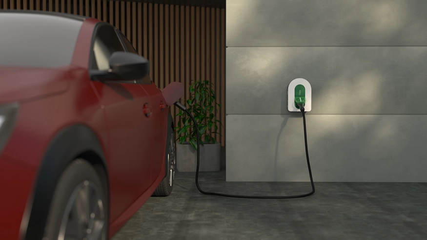 A red electric vehicle charging in a modern residential, connected to a wall-mounted Schneider Charge EV charger.