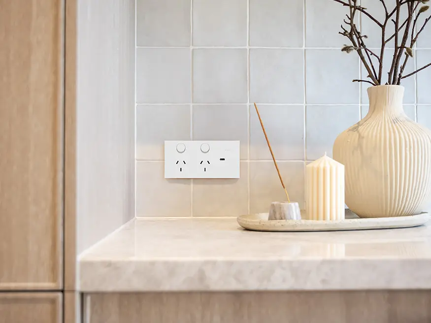 Clipsal Solis light switch and power point in white ceramic finish mounted on a tiled wall.