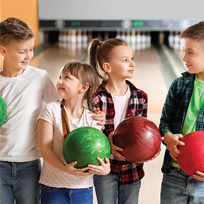 A group of children holding bowling balls in a bowling alley.