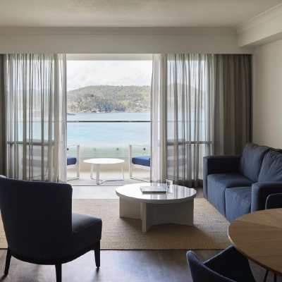 Modern living room with ocean view, blue sofa, chairs, and round coffee table.