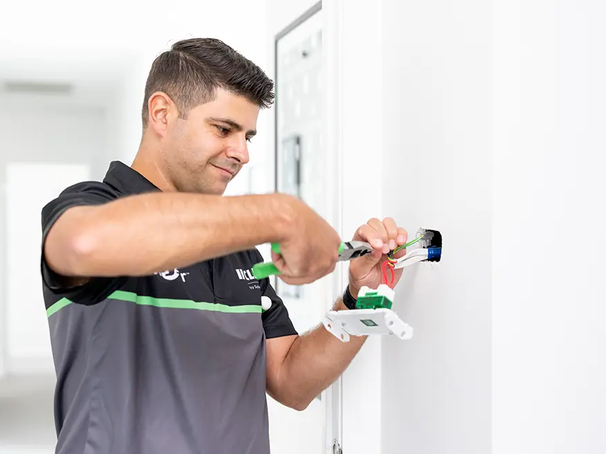 Electrician installing a wall outlet using a screwdriver.