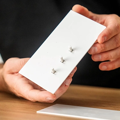 Person holding a Solis flush switch in white ceramic colorway.