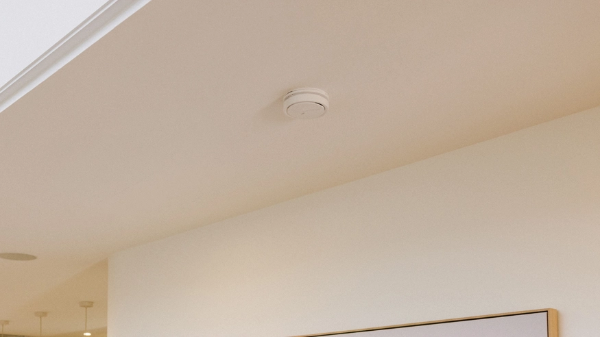 A Clipsal smoke alarm installed on the ceiling of a living room.