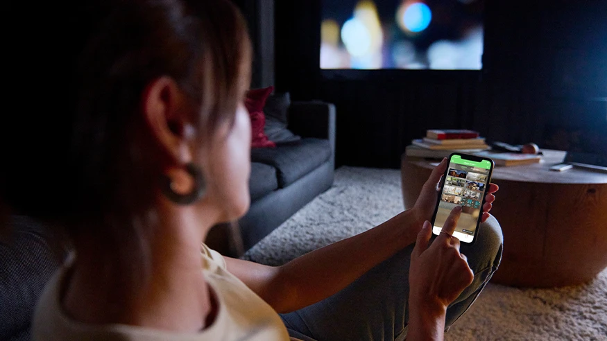 A homeowner uses the Wiser by SE app on her phone.