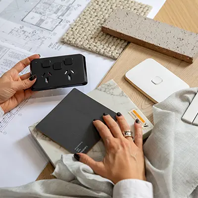 A designer inspects Clipsal switches and sockets from a Clipsal sample box.