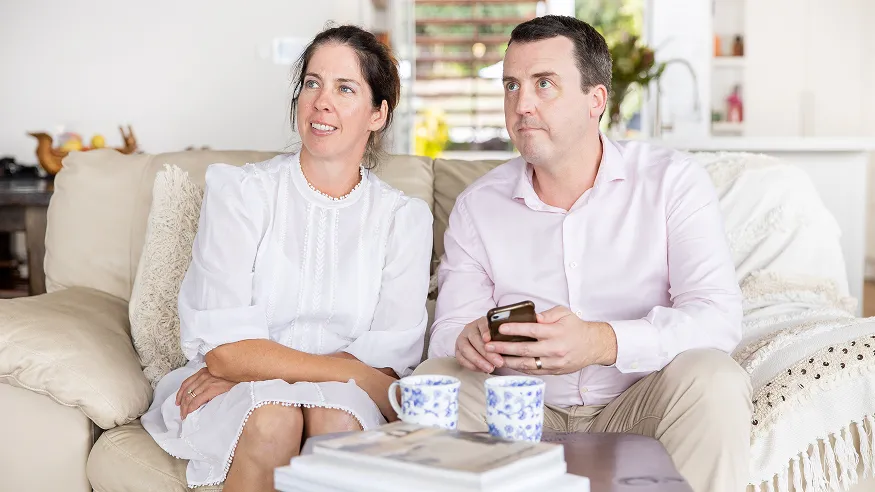 A couple of homeowners using Clipsal Wiser Smart Home on a smartphone.