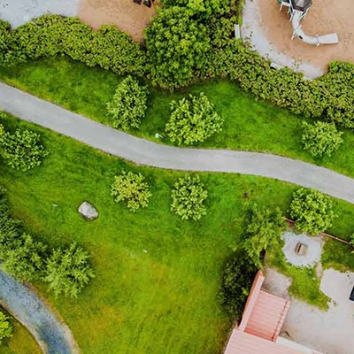 A bird’s eye view of a neighbourhood, showing trees, a playground, a waterway, and a house.
