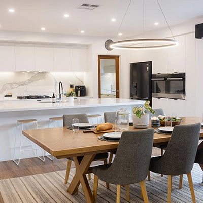 A contemporary kitchen featuring a dining table and chairs, illuminated by Clipsal downlights.