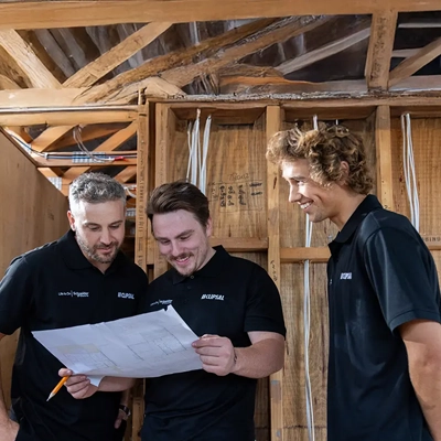 Three electricians wearing Clipsal-branded shirts discussing project plans.