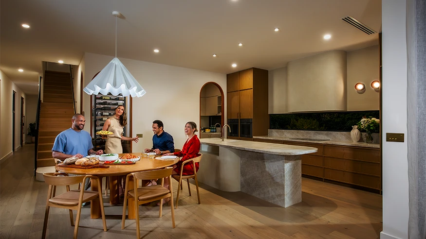 Brad and Tess with family in their home. Tess turns off a light with a Solis T Series switch.
