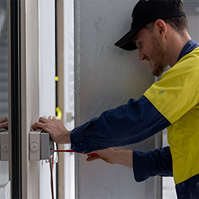 A man wearing a safety suit focused on his task with tools in hand.