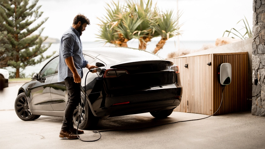 Neil plugs an EVlink home charger into an electric vehicle at Bunker House.