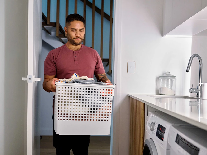 A homeowner walks into a laundry room with automatic motion sensor lights.