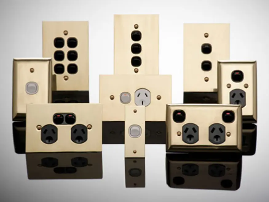 Collection of metal plate switches with various outlet and switch configurations arranged symmetrically on a reflective surface.