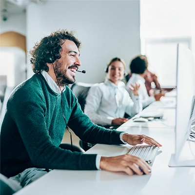 Smiling Clipsal tech support team staff with headset typing on keyboard in office.