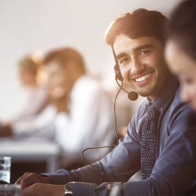 Customer support team in office, smiling staff wearing headsets at desks.