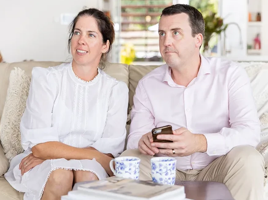 A couple of homeowners using Clipsal Wiser Smart Home on a smartphone.