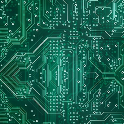 Close-up of a green printed circuit board with intricate conductive pathways and pads.