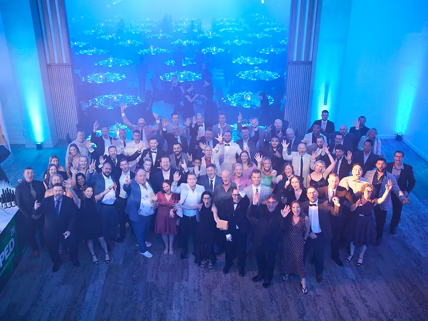 Large group of people posing together in a brightly lit event hall.