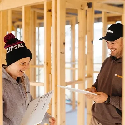 Steph and Chris Gee from Gee Electrical laughing while holding whiteboards.