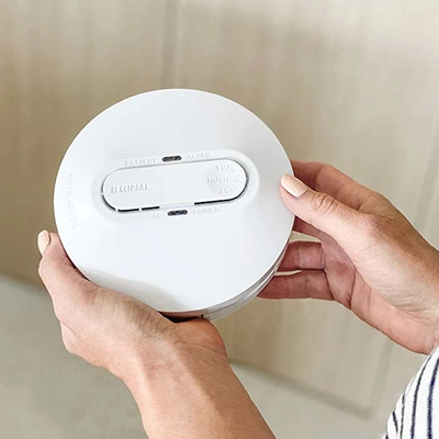 Hand holding a Clipsal smoke alarm.