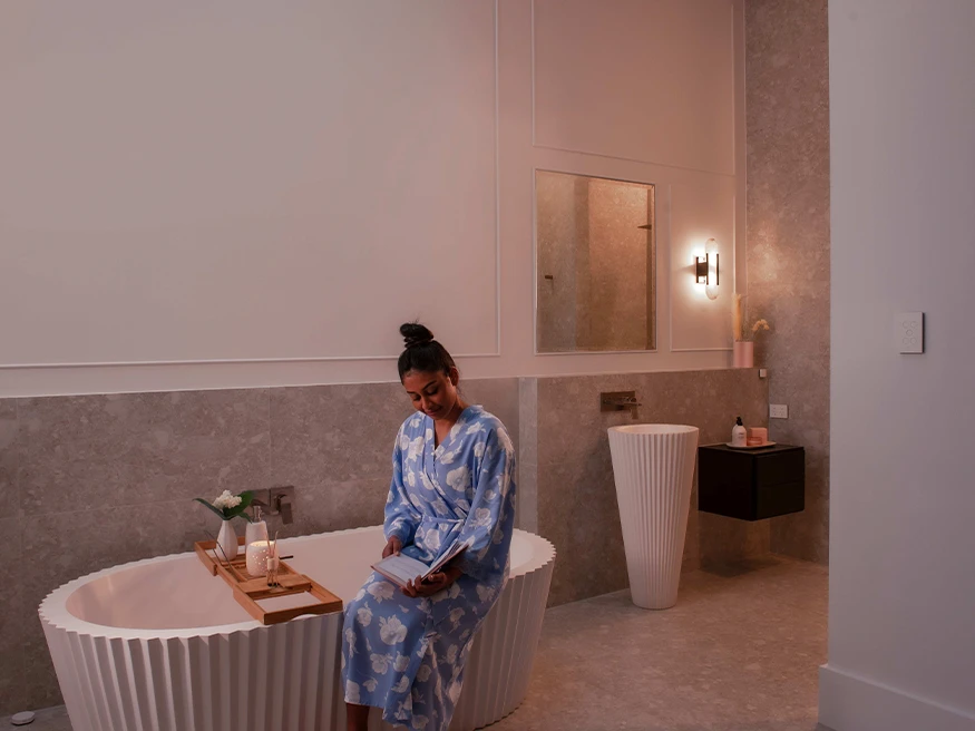 A homeowner using a smart home automation control system in a bathroom.