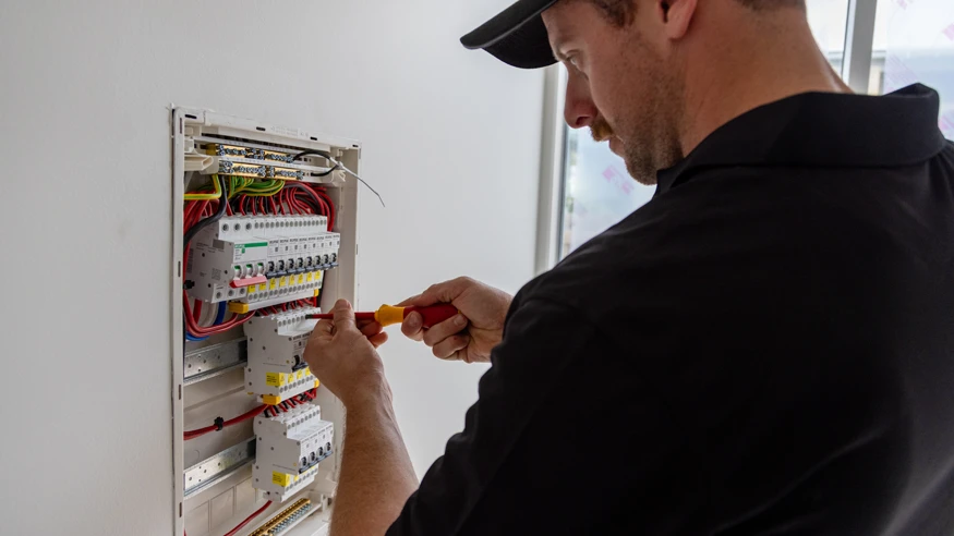 An electrician from Polar Industries tweaking a switchboard.